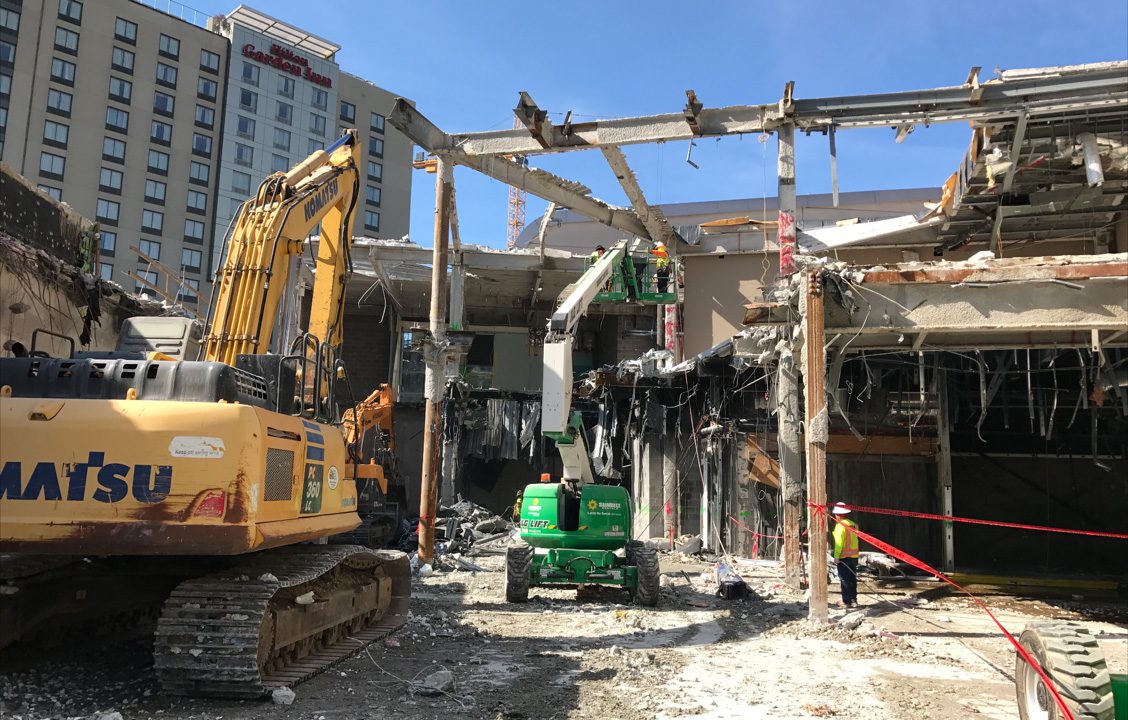 Yellow and green construction equipment demolishing a building